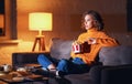 Young woman eats French fries and watches an exciting action-Packed movie on TV at home in evening alone