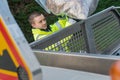 Young dustman putting collected leaves in lorry