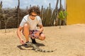 Young dutch man feeding iguana on ground Royalty Free Stock Photo