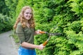 Young dutch woman pruning hedge with hedge trimmer Royalty Free Stock Photo