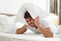 Sad man in bed covering head with pillow Royalty Free Stock Photo