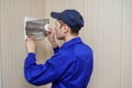 young electrician in blue overall disassembling a electrical panel with fuses in a house