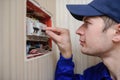 young electrician in blue overall disassembling a electrical panel with fuses in a house