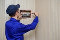 young electrician in blue overall disassembling a electrical panel with fuses in a house