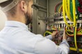 Young electrician measuring voltage in fuse board. Male technician examining fusebox with multimeter probe Royalty Free Stock Photo