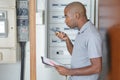 Young electrician measuring voltage in fuse board