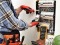 Young electrician technician at work on a electrical panel with