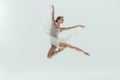 young elegant ballerina in white dress jumping in studio