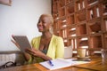 Young elegant and beautiful black African American business woman working online with digital tablet pad at coffee shop smiling ha Royalty Free Stock Photo