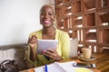 Young elegant and beautiful black African American business woman working online with digital tablet pad at coffee shop smiling ha Royalty Free Stock Photo