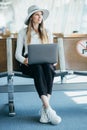 Young elegant business woman with hand luggage in international airport terminal, working on her laptop while waiting Royalty Free Stock Photo
