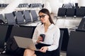 Young elegant business woman in international airport terminal, working on her laptop while waiting for flight Royalty Free Stock Photo