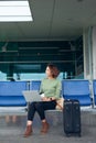 Young elegant business woman in international airport terminal, working on her laptop while waiting for flight Royalty Free Stock Photo