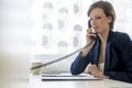 Young elegant businesswoman sitting at her office desk making a