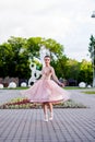 a young elegant female ballerina is dancing in the park, a lush organza skirt is flying apart from movement and dance