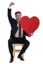 Young elegant man holding big red heart and celebrating Royalty Free Stock Photo