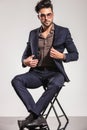 Young elegant man opening his coat sitting on chair Royalty Free Stock Photo