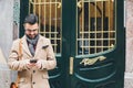 Young elegant man in a retro style using his smartphone at the front door Royalty Free Stock Photo