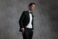 Young elegant man wearing tuxedo and holding hands in pockets Royalty Free Stock Photo