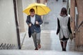 A young elegant man with a yellow umbrella is climbs the stairs in the city while it is raining. Walk, pedestrians, city