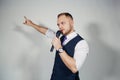 Young elegant talking man holding microphone talking with pointing finger. Isolated on grey background. Royalty Free Stock Photo