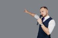 Young elegant talking man holding microphone talking with pointing finger. Isolated on grey background. Showman concept Royalty Free Stock Photo