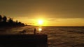 Young elegant woman dancing with hands up holding black scarf on the pier in sunset time.