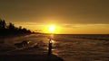 Young elegant woman dancing with hands up holding black scarf on the pier in sunset time.