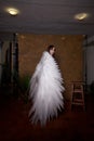 Young elegant woman in trendy black clothes with white wings. Brunette model in nice dark dress posing in studio in Royalty Free Stock Photo