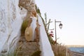 young elegant woman wearing straw hat and white dress standing on stars at old town - Greece, Spetses