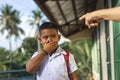 A young elementary student feels embarrassed after being scolded by an old man for loitering outside the school or being late. At Royalty Free Stock Photo