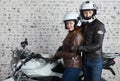 Young embracing couple in a motorcycle outfit standing together near the motorbike in the garage Royalty Free Stock Photo
