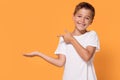 Young emotional little boy on orange studio background.