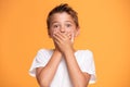 Young emotional little boy on orange studio background.