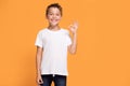 Young emotional little boy on orange studio background.