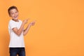 Young emotional little boy on orange studio background.