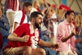 Young emotional people, sport fans attending live football match to cheer up favourite team. Sport enthusiasts