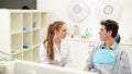 Young empathic female dentist listening to male patient complaints during dental consultation