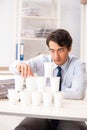 The young employee building pyramid from plastic cups Royalty Free Stock Photo
