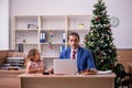 Young male employee celebrating Christmas at workplace with his Royalty Free Stock Photo