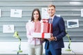 Young employees are standing with presents in the office. Royalty Free Stock Photo