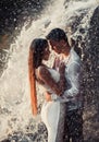 Young enamored couple hugs under spray of waterfall. Royalty Free Stock Photo