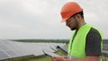 Young engineer is checking with tablet an operation of field of photovoltaic solar panels. Solar panel field. Clean