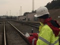 Young Engineer coordinating work using modern tablet. Railway employee in safety west and helmet railway on background.