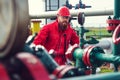 Engineer in hard-hat. Face behind pipeline machinery, fuel and oil refinery.