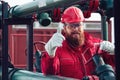 Engineer in hard-hat. Face behind pipeline machinery, fuel and oil refinery.