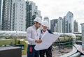 Young engineer hold drawing plan of building and discuss with senior coworker and they also stay on rooftop of construction site