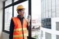 A young engineer stands with a walkie-talkie talking to a team of coordinating engineers at a construction site. Royalty Free Stock Photo