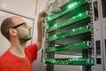 Young engineer switches wires in a rack with telecommunication equipment. The technician supports the work of the data center. Royalty Free Stock Photo