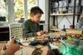 Passion that builds excellence. Young engineer using soldering iron to join chips and wires. Robotics and software Royalty Free Stock Photo